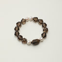A close-up of the consecrated Yue TerraBrio bracelet with rare 99-sink Kynam beads, hexagonal smoky quartz prisms, and Thai silver spacers.