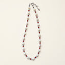 Tidebound Resolve trochus shell, red agate, and aquamarine necklace arranged on a cream background.