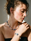A model wearing the Yue TerraBrio Jewelry, a temple-blessed Cosmic Intuition necklace and matching bracelet set under warm, dramatic sunlight, showcasing modern spiritual elegance.