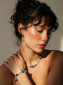 A model wearing the temple-blessed Cosmic Intuition necklace and matching bracelet set from Yue TerraBrio, under warm, dramatic sunlight, showcasing modern spiritual elegance.