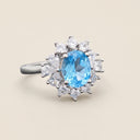 Angled view of Azure Halo adjustable S925 sterling silver ring with oval blue topaz and floral halo setting.