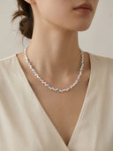 Model wearing the Yue TerraBrio "Azure Horizon" necklace featuring 3D teardrop Blue Topaz and double-sided polished Baroque pearls for Throat Chakra alignment.
