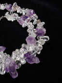 Close-up of clear quartz chips and irregular amethyst stones against a black background.