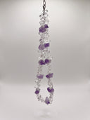 Clear quartz and amethyst necklace hanging against a light neutral background.
