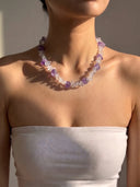 Model wearing the clear quartz and amethyst necklace with a white strapless top.
