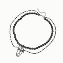 Eclipse Wing layered black spinel and clear quartz necklace with a butterfly-and-teardrop charm on a white background.