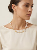 Model wearing the Yue TerraBrio "Luminous Manifest" necklace, showing the unique organic textures of baroque pearls and citrine against a cream-toned silk outfit.