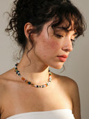 Model wearing the Yue TerraBrio "Radiant Spectrum" necklace, showcasing the eclectic and vibrant mix of natural stones against a neutral-toned garment.