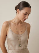 Model wearing the Yue TerraBrio "Verdant Flow" necklace, showing the elegant drape of the green amethyst egg and the diverse multi-gemstone beads against a silk garment.