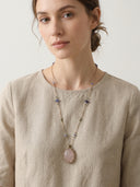 Model wearing the Yue TerraBrio Rose Quartz egg necklace, a long bohemian-style intentional piece designed for emotional harmony and spiritual grounding.
