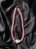 Pink cat’s eye and baroque pearl necklace arranged on black silk.