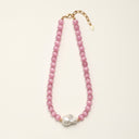 Full product view of the pink cat’s eye and baroque pearl necklace on a light background.