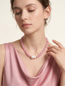 Close-up of a model wearing the Rosy Poise pink cat’s eye necklace with a freshwater baroque pearl focal bead.