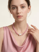 Front view of a model wearing the Rosy Poise necklace with pink cat’s eye beads and a baroque pearl focal bead.