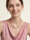 Model smiling while wearing the Rosy Poise pink cat’s eye and baroque pearl necklace.