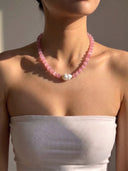 Model wearing the pink cat’s eye and baroque pearl necklace with a light strapless top.