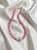 Rosy Poise pink cat’s eye and baroque pearl necklace arranged on white silk.