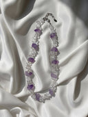 Clear quartz chip and amethyst necklace displayed on white silk in natural light.