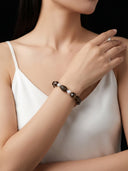 Model wearing the Yue TerraBrio "Sacred Stillness" bracelet, featuring dark resinated Kynam agarwood and hexagonal smoky quartz for executive grounding.