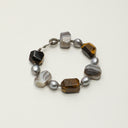A Yue TerraBrio bracelet featuring faceted yellow tiger's eye, freeform Persian agate, and 9-10mm grey baroque pearls with a Thai silver clasp.