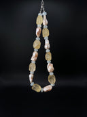 Full product view of the citrine, aquamarine, and baroque pearl necklace against a black background.