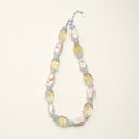 Sunlit Ease necklace with lemon citrine, pale blue aquamarine, and baroque pearls arranged on a cream background.