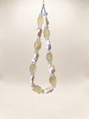 Full view of the citrine, aquamarine, and baroque pearl necklace hanging against a light background.