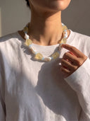 Model wearing a citrine, aquamarine, and baroque pearl necklace with a white long-sleeve top.