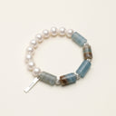 Full product view of the blue onyx and freshwater pearl bracelet on a cream background.
