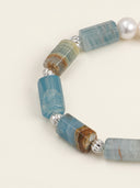 Close-up of blue onyx cylinder beads, freshwater pearl, and sterling silver twisted spacer beads.