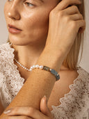 Model wearing the blue onyx and freshwater pearl bracelet with a neutral lace top.