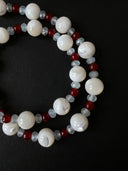 Close-up of trochus shell, red agate, and faceted aquamarine beads against a black background.
