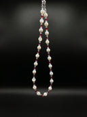 Full product view of the trochus shell, red agate, and aquamarine necklace against a black background.