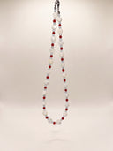 Full view of the trochus shell, red agate, and aquamarine necklace hanging against a light background.