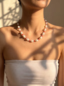 Model wearing the trochus shell, red agate, and aquamarine necklace with a white strapless top.