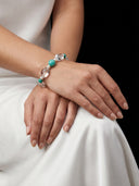 Close-up of Yuè TerraBrio Amazonite resonance bracelet on model's wrist against white silk, showcasing the premium high-vibe crystal texture.
