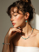 Model wearing Yuè TerraBrio Amazonite necklace and matching jewelry set in intense warm sunlight, showcasing the vibrant blue-green tones against the skin.