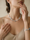 High-fashion close-up of Yuè TerraBrio Azure Intuition necklace and matching bracelet set on model, showcasing minimalist sterling silver and blue gemstones