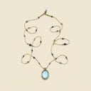 The "Serene Multi-Treasure" necklace by Yuè TerraBrio, featuring a large oval Blue Topaz pendant and a 66-stone Duo Bao strand for clarity, harmony, and manifestation.
