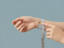 Hands using a soft measuring tape to measure wrist size for the Yue TerraBrio bracelet size guide.