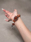 Model wearing the Yue TerraBrio Crimson Garden red hematoid quartz bracelet with shell pearl and aged titanium steel floral details.