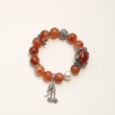 Yue TerraBrio Crimson Garden bracelet with 12–13mm red hematoid quartz beads, shell pearl, aged titanium steel floral details, and dangling charms.