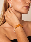Model wearing the Yue TerraBrio Golden Flow Brazilian citrine and freshwater pearl bracelet with a pearl earring in warm natural light.