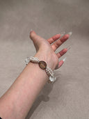 Model wearing the Yue TerraBrio Grounded Clarity smoky quartz, clear quartz, and shell pearl bracelet on a neutral background.