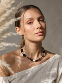 Artistic lifestyle portrait of a model wearing the Yuè TerraBrio smoky quartz necklace in warm natural light, highlighting its sculptural crystal form.