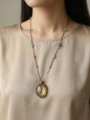 A model wearing the Yuè TerraBrio "Solar Resonance" necklace, featuring a large Lemon Citrine pendant and a 37-stone Duo Bao strand for manifestation, joy and wealth.