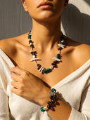 Necklace and bracelet set on a person wearing a beige top against a neutral background