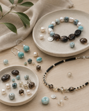 Natural gemstone beads, pearls, and jewelry pieces arranged on ceramic trays for Yue TerraBrio’s intention-led jewelry design process.