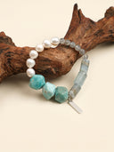 Full view of the Ocean Current Amazonite, blue onyx, and grey moonstone bracelet arranged with natural wood.