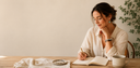 A woman wearing Yue TerraBrio gemstone jewelry while journaling in a calm modern daily ritual setting.